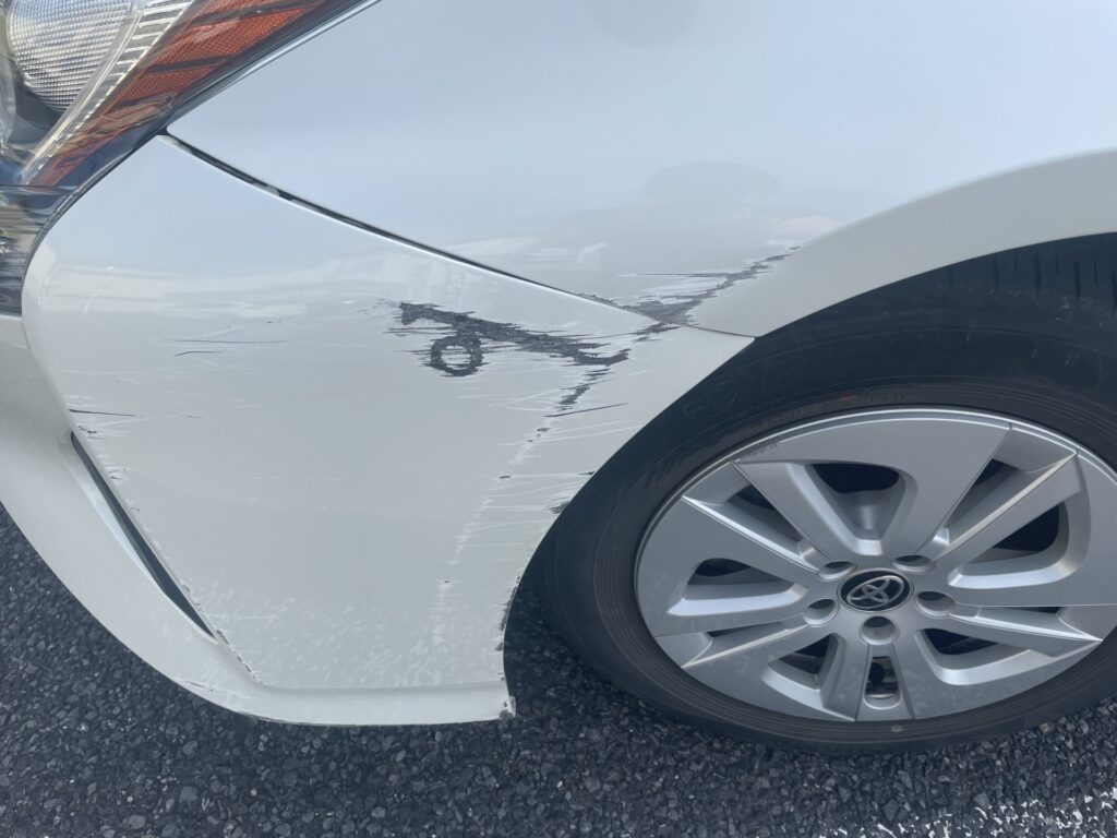 フロントフェンダーの塗膜が剥がれた白い車