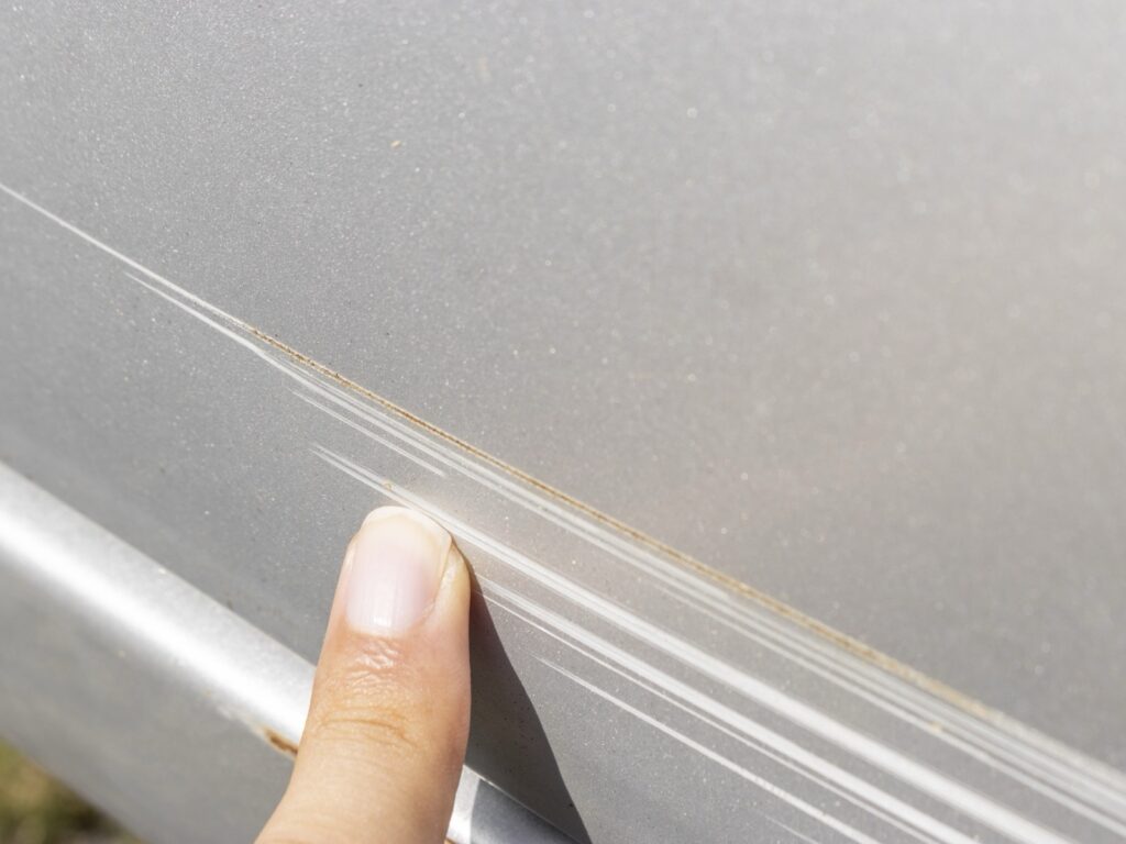 車体の擦り傷を指でたどって確認している様子