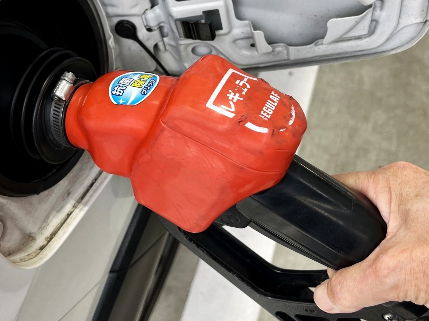 白い車の給油口にガソリンの給油ノズルを差し込んだ様子