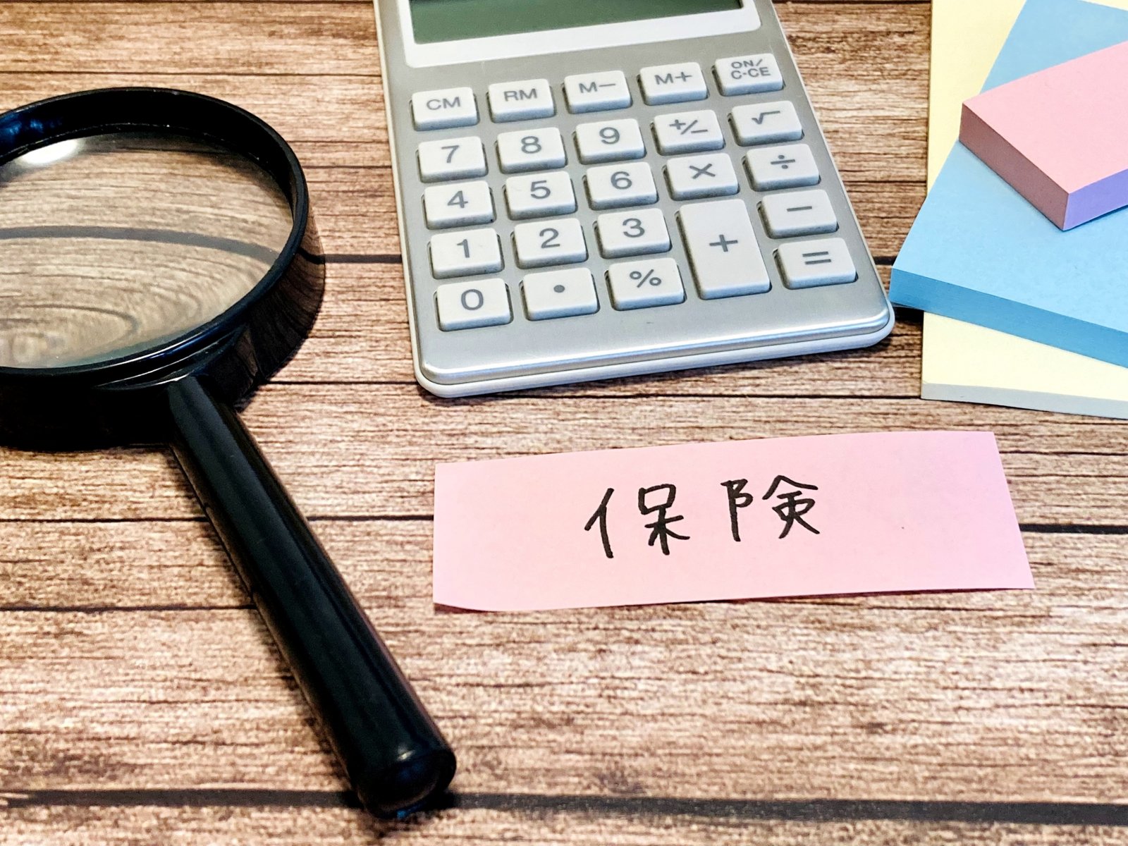 虫眼鏡と電卓と「保険」と書いた付箋